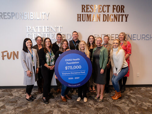 Group photo of Gesa Credit Union and CHAS Health Foundation representatives holding a large sign recognizing a $75,000 multi‑year donation to the CHAS Health Foundation Employee Emergency Fund for 2025–2027, standing together indoors beneath wall text reading “Respect for Human Dignity.”