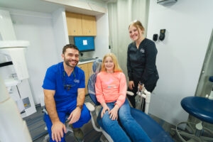 Two CHAS Health staff sitting next to a juvenile patient inside the mobile dental clinic.