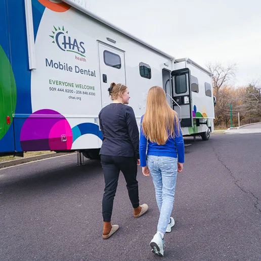 CHAS Health mobile dental clinic now open, parked outdoors as two people walk toward the clinic entrance.
