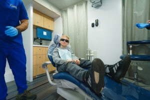 Child reclining in a mobile dental clinic exam chair during a dental visit.
