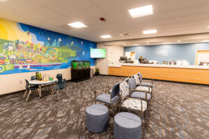 Lobby of Spokane Pediatrics with a bright, kid-friendly design, featuring a colorful wall mural, a children’s play table, aquarium, patterned seating, and a reception desk with the CHAS Health logo in a clean, modern waiting area.